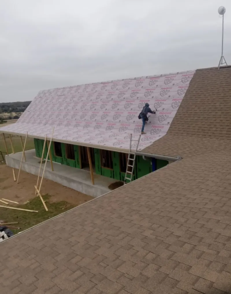 Worker preparing underlayment for a metal roof installation in White House